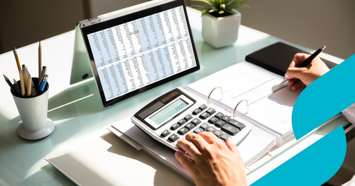 Someone at a desk with figures on a spreadsheet on an ipad with folders and a calculator