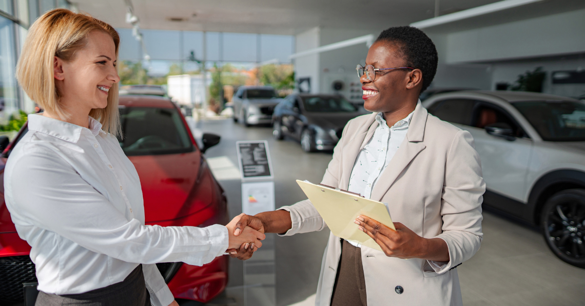 Image of two business women shaking hands in a car dealership